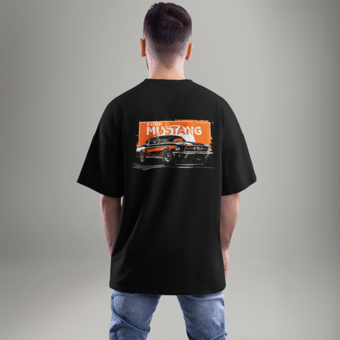 mustang--back-closeup "Black oversized t-shirt featuring a vintage Ford Mustang graphic on the back with an orange grunge background – worn by a male model facing away."