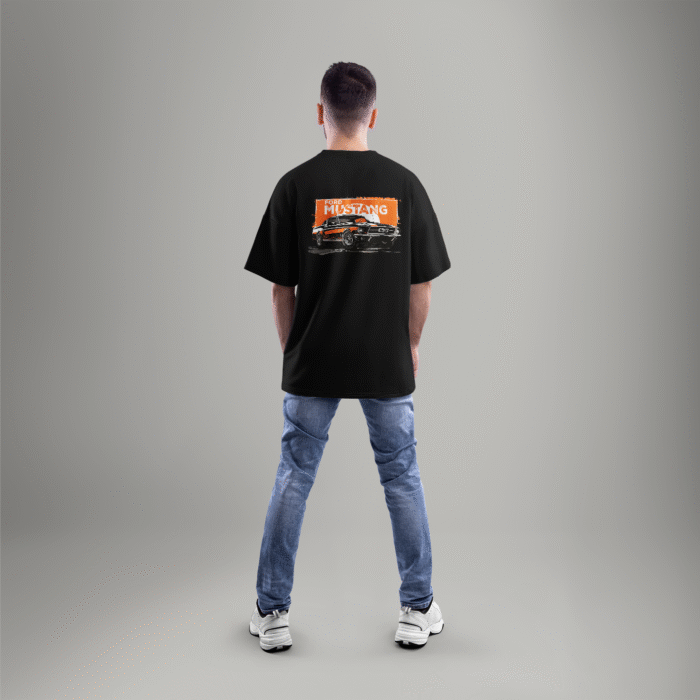 mustang-back-full Black oversized t-shirt featuring a vintage Ford Mustang graphic on the back with an orange grunge background – worn by a male model facing away.